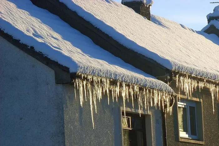 苏格兰冰雪覆盖的屋顶上悬着冰柱