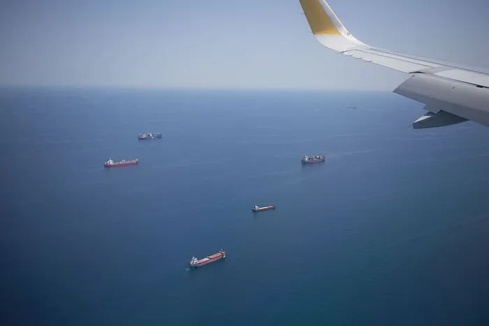 从飞机窗口俯瞰海上货船，飞机机翼在空中