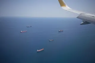 从飞机窗口俯瞰海上货船，飞机机翼在空中