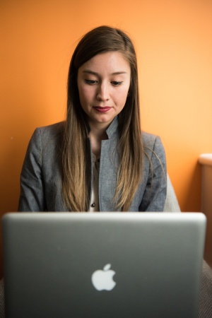 穿着灰色西装外套、使用银色苹果Macbook的女士