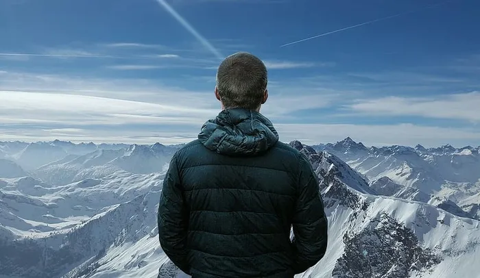 照片中的人站在雪峰的山顶上。