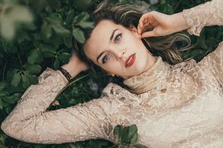 身穿棕色花朵高领长袖衫的女子躺在绿色草地上