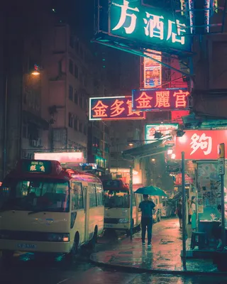 在停靠的公共汽车附近手持雨伞行走的人