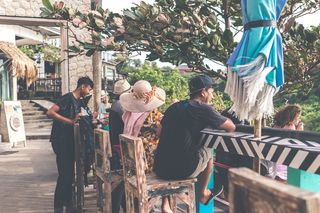 一名身穿黑色T恤和棕色短裤的男子坐在棕色的木凳上