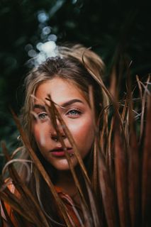 一个女人在干树叶后面的特写照片