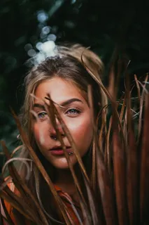 一个女人在干树叶后面的特写照片