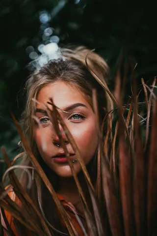 一个女人在干树叶后面的特写照片