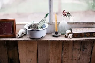 棕色墙上黄色蜡烛旁的白色金属碗