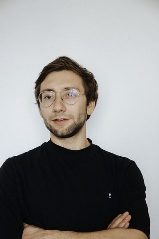 微笑的男人穿着黑色运动衫，戴着眼镜