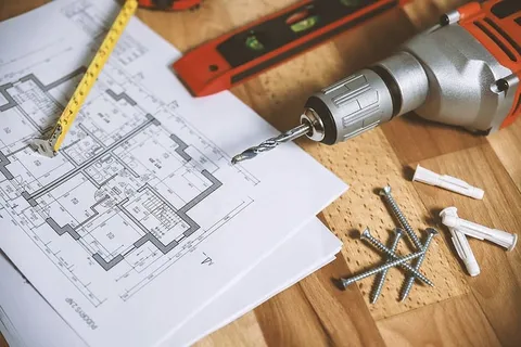 木背景上的特写钻孔工具和公寓平面图 木背景上的特写钻孔工具和公寓平面图