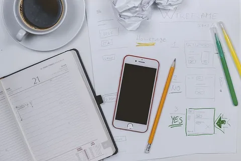 Web开发者制作一些原型。桌上有咖啡、日记和智能手机