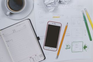 Web开发者制作一些原型。桌上有咖啡、日记和智能手机