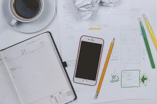 Web开发者制作一些原型。桌上有咖啡、日记和智能手机