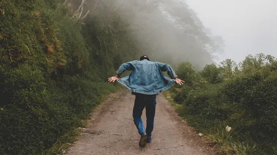 在雾气弥漫的道路上行走时穿着蓝色牛仔夹克的人 在雾气弥漫的道路上行走时穿着蓝色牛仔夹克的人