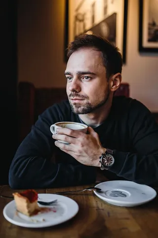 年轻的衣着优雅的男子坐在咖啡馆里