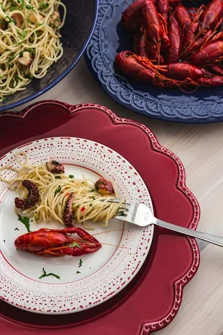 精美的晚餐，搭配海鲜意大利面、小龙虾和红酒，餐桌上装饰着玫瑰