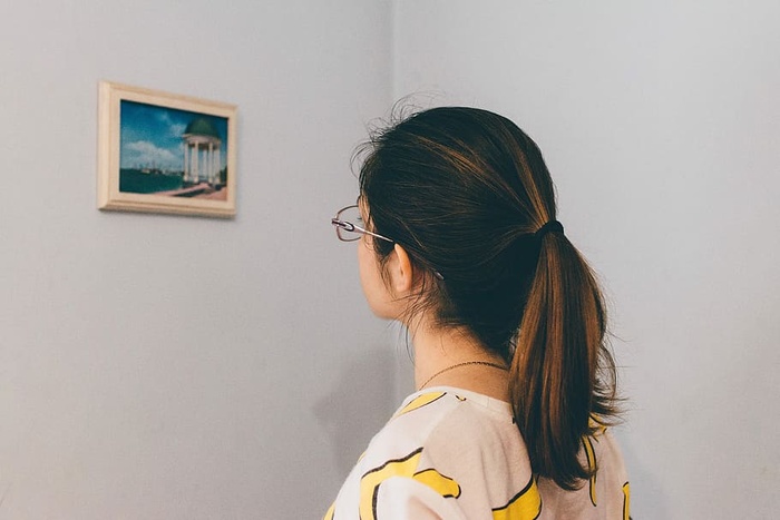 戴眼镜的女人站着盯着墙上的画