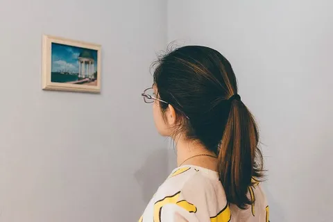 戴眼镜的女人站着盯着墙上的画 戴眼镜的女人站着盯着墙上的画