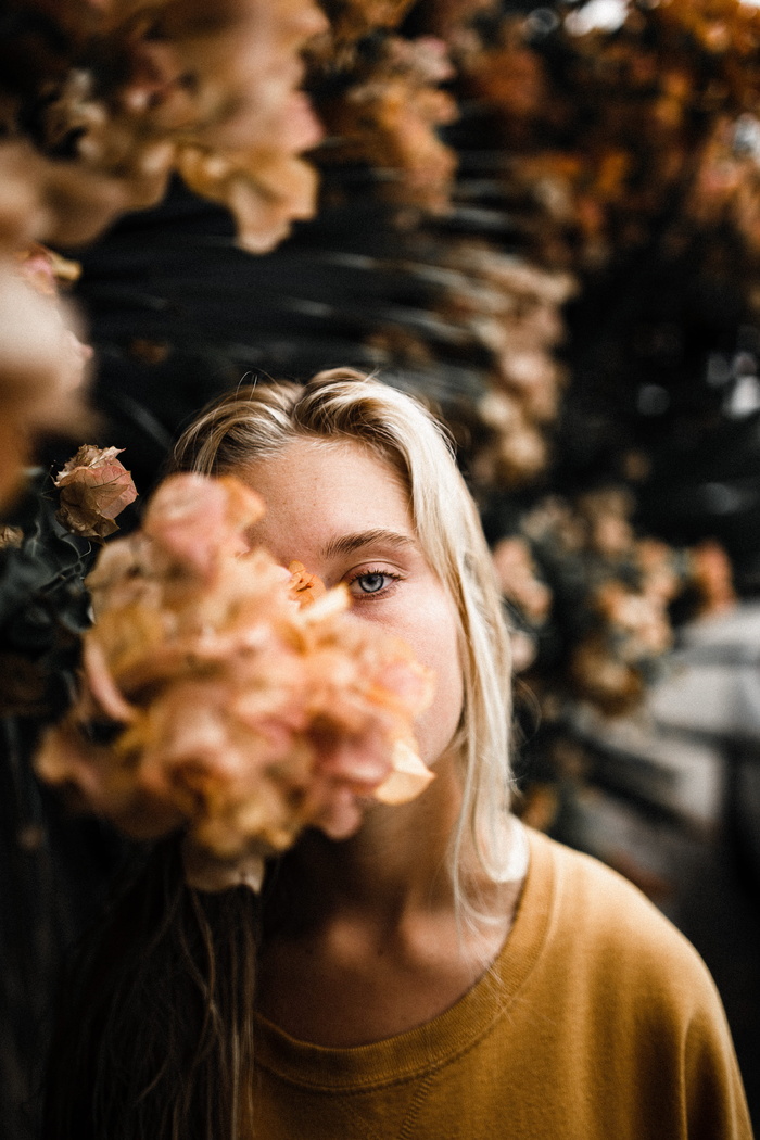 白天在棕色花朵旁穿着米色上衣的女人