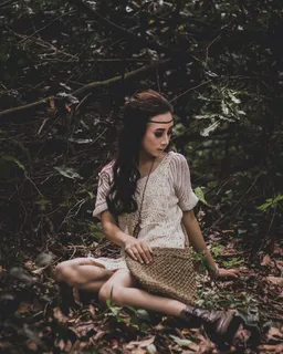 坐在被植物包围的干树叶上的女人照片 坐在被植物包围的干树叶上的女人照片