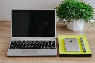 银色宏碁笔记本电脑、一部白色苹果iPhone和一个放在木桌上的记事本