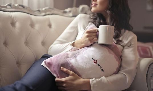 客厅里，一位年轻的黑发女子坐在沙发上，手里拿着一个咖啡杯