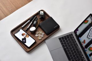 打开笔记本电脑旁边的电话，钱包，手表，钢笔，硬币的顶部的木制托盘