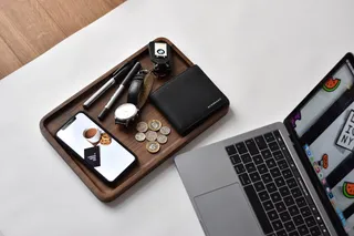 打开笔记本电脑旁边的电话，钱包，手表，钢笔，硬币的顶部的木制托盘