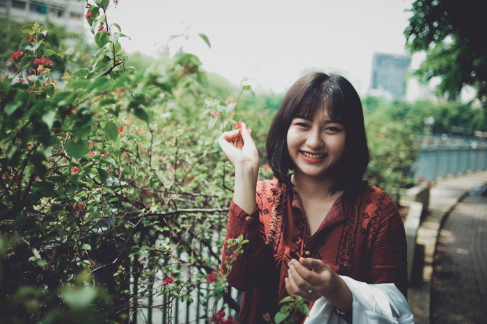 身穿红领衬衫的女子站在植物旁边