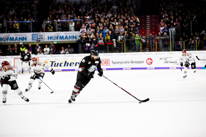 人们在球场上打曲棍球，旁边有人观看