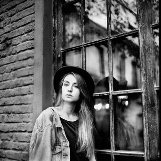 斜靠在窗户上的女式牛仔夹克和帽子的灰度照片