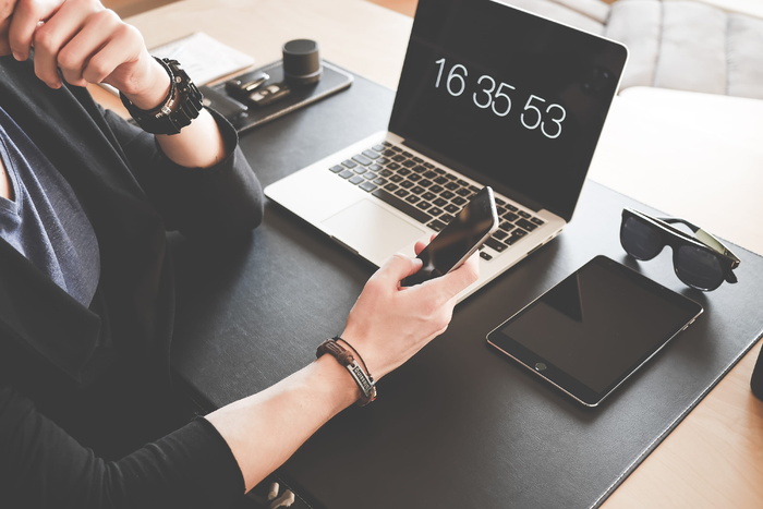 面对Macbook Pro和黑色Ipad时使用智能手机的女性