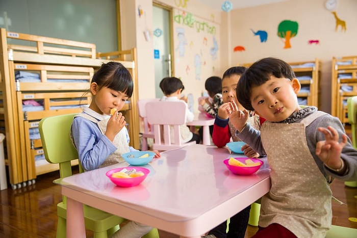 三个蹒跚学步的孩子在白色的桌子上吃东西