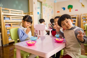 三个蹒跚学步的孩子在白色的桌子上吃东西