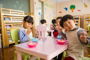 三个蹒跚学步的孩子在白色的桌子上吃东西