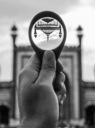 举着圆形放大镜的人的灰度照片