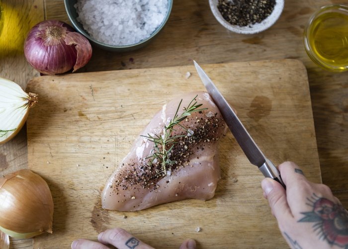 在砧板上切生肉和胡椒的人，旁边放着香料
