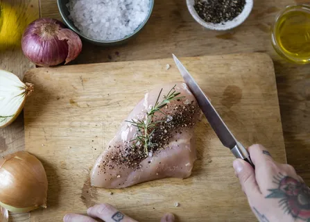 在砧板上切生肉和胡椒的人,旁边放着香料 在砧板上切生肉和胡椒的人,旁边放着香料