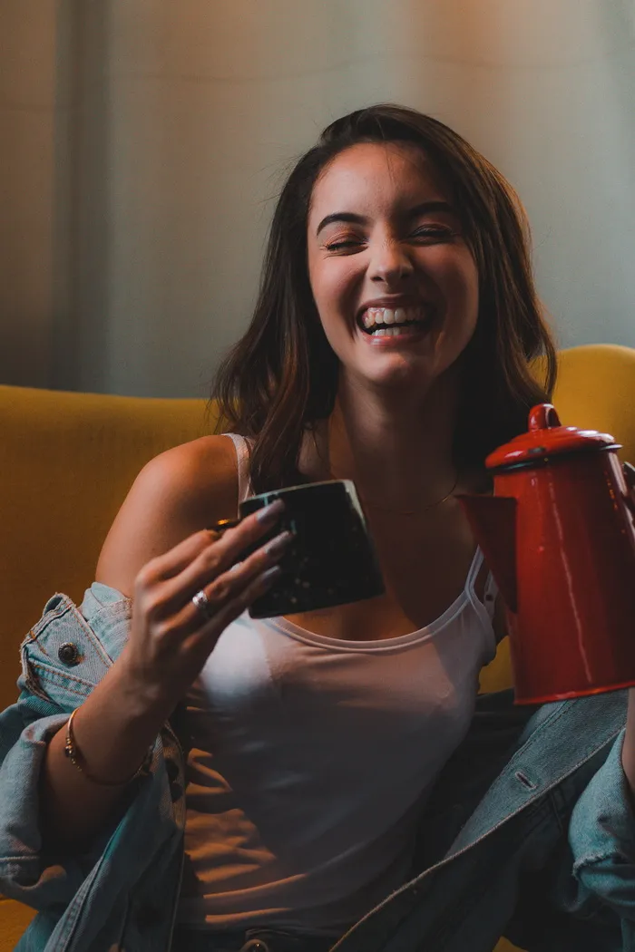 拿着马克杯和水壶笑的女人的照片