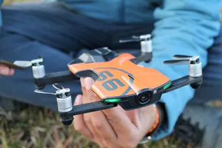 手持橙色和黑色无人机的人