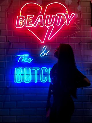 站在红色和蓝色霓虹灯标志附近的女性