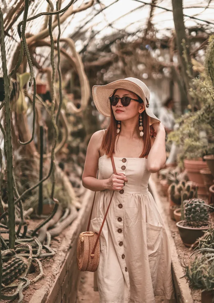 身穿无袖连衣裙的女子在仙人掌植物附近行走