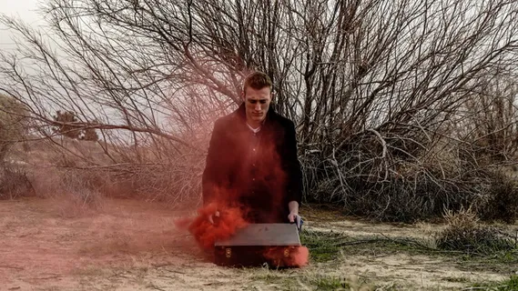 一名男子在地上打开手提箱，红色的烟雾从箱子中逃走。