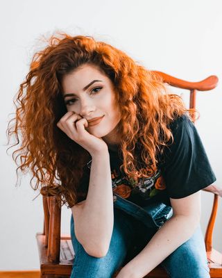 女人坐在椅子上，右手放在脸颊上