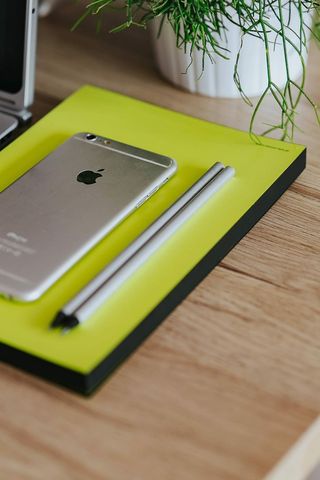 银色宏碁笔记本电脑、一部白色苹果iPhone和一个放在木桌上的记事本