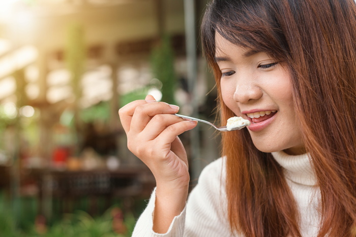 拿着勺子吃白色食物的女人