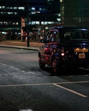 夜间在灰色混凝土道路上行驶的黑色车辆