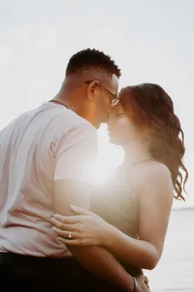 一名身穿白衬衫的男子吻着一名女子的鼻子