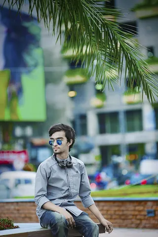 一名身穿灰色衬衫的男子坐在大楼附近的长凳上