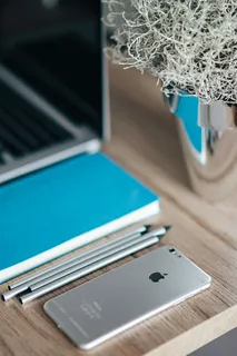 银色iPhone配蓝色笔记本和铅笔